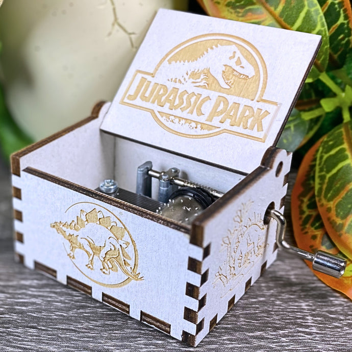 Jurassic Park: Join Alan Grant, Ellie Sattler, and Ian Malcolm on a tour of an island theme park filled with genetically resurrected dinosaurs. Get ready for an adventure with our iconic music box by MarketPlaceFad - Malaura Ashley.
