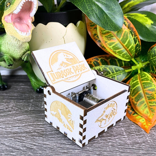 Jurassic Park: Join Alan Grant, Ellie Sattler, and Ian Malcolm on a tour of an island theme park filled with genetically resurrected dinosaurs. Get ready for an adventure with our iconic music box by MarketPlaceFad - Malaura Ashley.