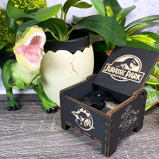 Jurassic Park: Join Alan Grant, Ellie Sattler, and Ian Malcolm on a tour of an island theme park filled with genetically resurrected dinosaurs. Get ready for an adventure with our iconic music box by MarketPlaceFad - Malaura Ashley.