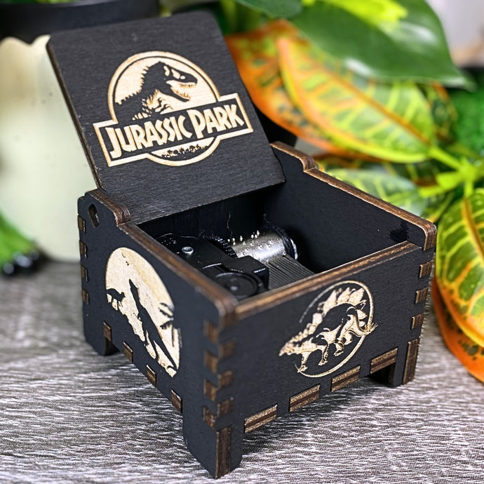 Jurassic Park: Join Alan Grant, Ellie Sattler, and Ian Malcolm on a tour of an island theme park filled with genetically resurrected dinosaurs. Get ready for an adventure with our iconic music box by MarketPlaceFad - Malaura Ashley.