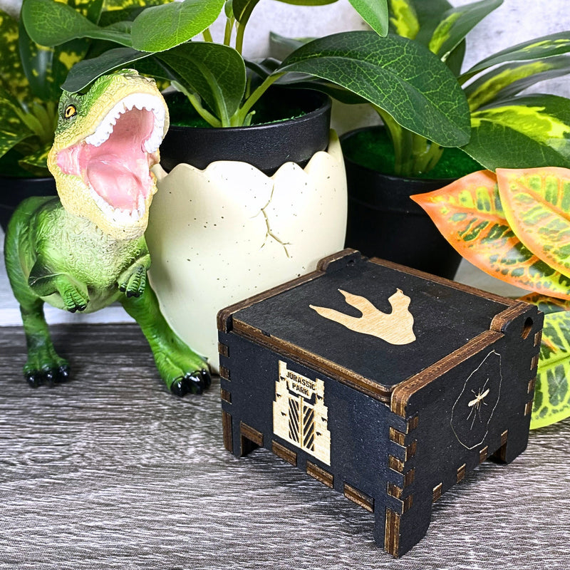 Load image into Gallery viewer, Jurassic Park: Join Alan Grant, Ellie Sattler, and Ian Malcolm on a tour of an island theme park filled with genetically resurrected dinosaurs. Get ready for an adventure with our iconic music box by MarketPlaceFad - Malaura Ashley.
