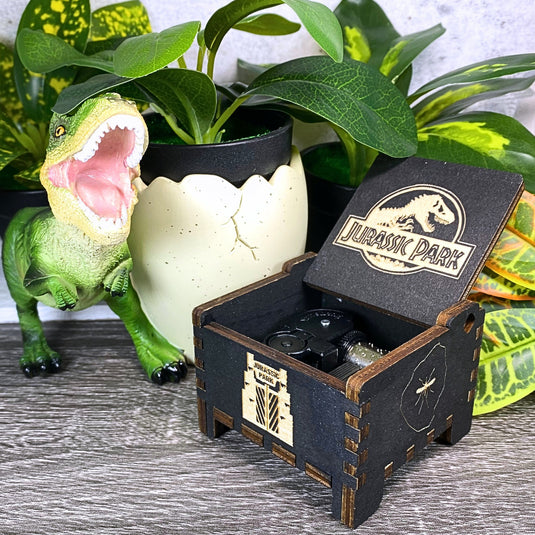Jurassic Park: Join Alan Grant, Ellie Sattler, and Ian Malcolm on a tour of an island theme park filled with genetically resurrected dinosaurs. Get ready for an adventure with our iconic music box by MarketPlaceFad - Malaura Ashley.