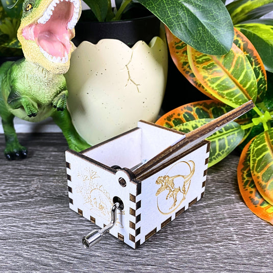 Jurassic Park: Join Alan Grant, Ellie Sattler, and Ian Malcolm on a tour of an island theme park filled with genetically resurrected dinosaurs. Get ready for an adventure with our iconic music box by MarketPlaceFad - Malaura Ashley.