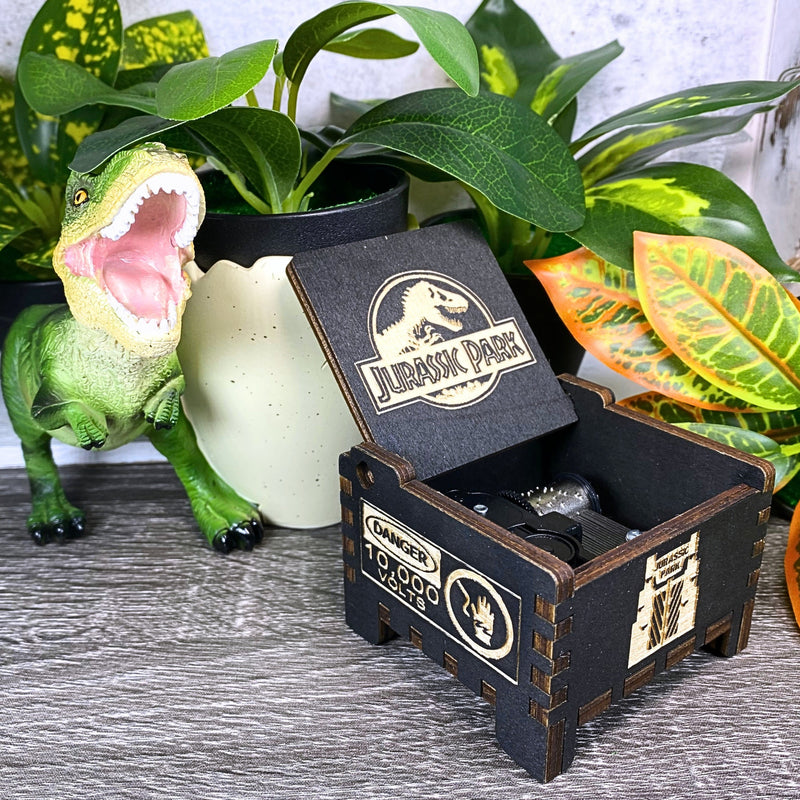 Load image into Gallery viewer, Jurassic Park: Join Alan Grant, Ellie Sattler, and Ian Malcolm on a tour of an island theme park filled with genetically resurrected dinosaurs. Get ready for an adventure with our iconic music box by MarketPlaceFad - Malaura Ashley.
